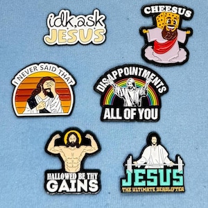 May include: Set of ten enamel pins featuring humorous and irreverent depictions of Jesus. The pins feature phrases like "idk ask Jesus", "Hallowed be thy gains", and "Jesus the ultimate deadlifter".