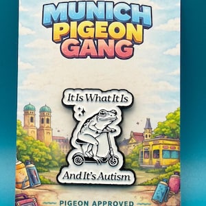 Könnte beinhalten: Ein Ansteckpin mit einer Frosch-Cartoonfigur auf einem Roller, mit dem Text "It Is What It Is And It's Autism". Der Pin befindet sich auf einer Karte mit den Worten "Munich Pigeon Gang" und "Pigeon Approved".