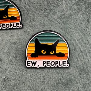 Può includere: Gatto nero che sbircia sopra un tramonto retrò con il testo "EW, PEOPLE."