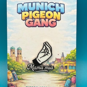 Könnte beinhalten: Ein Metall-Emaille-Pin mit einer weißen Hand, die eine italienische Geste macht, mit dem Text Mama mia darunter. Der Pin ist auf einer rechteckigen Trägerkarte befestigt, die oben MUNICH PIGEON GANG und unten PIGEON APPROVED anzeigt.