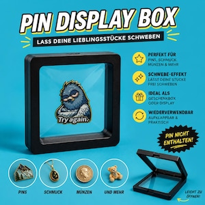 Könnte beinhalten: Schwarze Pin-Display-Box mit dem Text "PIN DISPLAY BOX" und "LASS DEINE LIEBLINGSSTÜCKE SCHWEBEN". Die Box ist geöffnet und zeigt einen blauen Hintergrund und eine Cartoon-Taubennadel. Für Pins, Schmuck, Münzen und mehr.