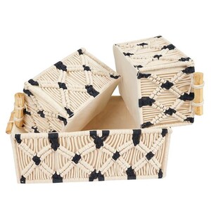May include: Three rectangular macrame baskets in a neutral color palette. The baskets feature a woven design with black accents and bamboo handles. The open design of the baskets makes them suitable for storage or display.