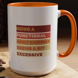 May include: White ceramic coffee mug with an orange rim and handle. The mug has a retro-style design with the text "Being a Functional Adult Everyday Seems a Bit Excessive" in red, orange, and yellow.
