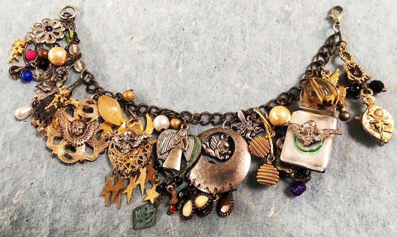 May include: A charm bracelet with a variety of charms, including angels, stars, hearts, and a crescent moon. The bracelet is made of metal and has a silver tone finish.