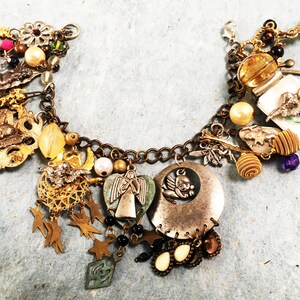 May include: A gold charm bracelet with a variety of charms, including an angel, a bird, a star, and a heart. The bracelet is made of metal and has a chain link design.