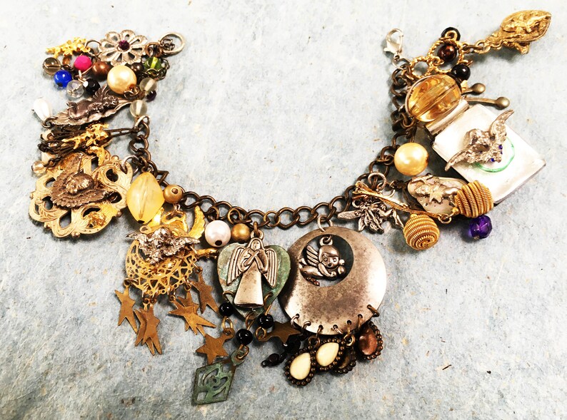 May include: A gold charm bracelet with a variety of charms, including an angel, a bird, a star, and a heart. The bracelet is made of metal and has a chain link design.