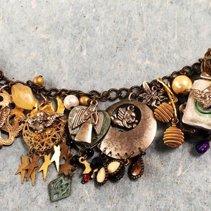 May include: A gold charm bracelet with a variety of charms, including angels, stars, and a crescent moon. The bracelet is made of metal and has a chain link design.