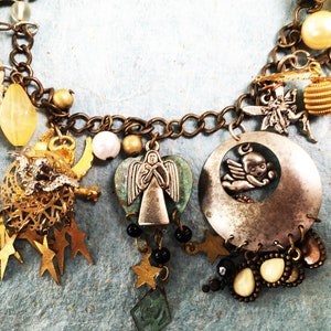 May include: A silver charm bracelet with a variety of charms, including a heart-shaped charm with an angel, a crescent moon charm with a cherub, and a star charm. The bracelet is made of brass and has a silver finish.