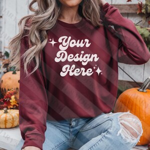 May include: A maroon sweatshirt with long sleeves and a crew neck. The sweatshirt has the text "Your Design Here" in white with a retro font and sparkling stars on either side of the text.