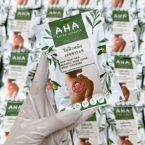 May include: A white and green package of AHA Extra Vitamin body cleanser. The package features a person with a red rash on their shoulder, a green leaf design, and the text "ไล่สิวหลัง เร่งขาวx5" in Thai. The text "AHA BHA PHA Miracle Acne Clear Body Cleanser" is also on the package.