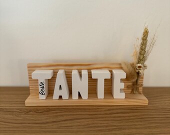 Letras sobre madera con un pequeño ramo de flores secas.