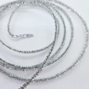 May include: Silver tinsel craft wire, a sparkly, metallic, and flexible material used for crafting and decorating.