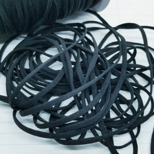 May include: A close-up of a spool of black elastic cord. The cord is tightly wound and appears to be made of a soft, stretchy material.