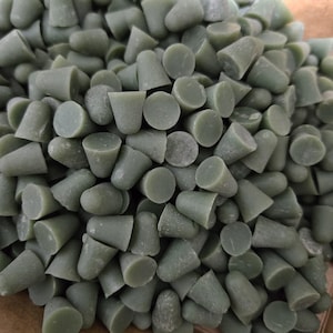 May include: A collection of small, olive-green, cone-shaped items. Each item has a flat, circular base and a conical top. The items are closely packed together, filling the frame. The overall texture appears slightly rough.