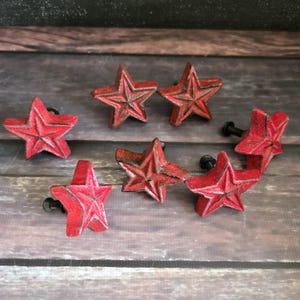 May include: Seven red cast iron star-shaped drawer pulls with black screw attachments.