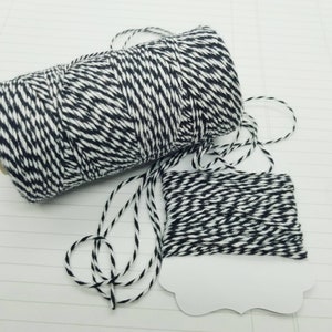 May include: Two spools of black and white baker's twine. The twine is wound around a cardboard spool.