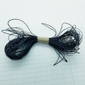 May include: A spool of black twine tied with a brown tape label. The twine is made of natural fibres and is ideal for crafts, gardening, and packaging.