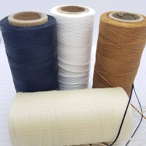 May include: Four spools of waxed thread in different colours: black, white, brown, and cream. The spools are made of cardboard and have a paper label.