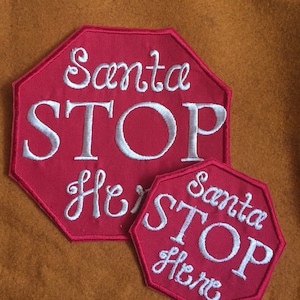 May include: Two red stop sign shaped patches with white embroidered text. The larger patch says "Santa Stop Here" and the smaller patch says "Santa Stop Here".
