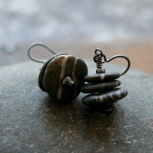 May include: A pair of earrings made with stacked, round, gray and white striped stones. The stones are attached to silver wire hooks.