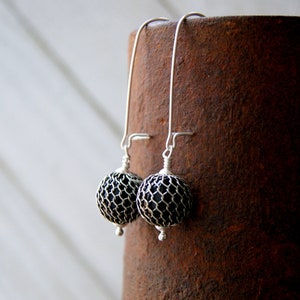 May include: A pair of silver dangle earrings with black wire mesh spheres.