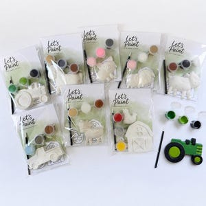 May include: A collection of paint-your-own farm animal and vehicle kits. Each kit includes a plaster figure, paint pots, and a paintbrush. The kits feature a tractor, truck, pig, sheep, cow, chicken, and barn. The packaging reads "Let's Paint".