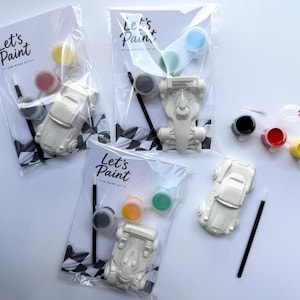 May include: Car paint kits with the text "Let's Paint" on the packaging. Each kit includes a white car model, paint pots in various colors, and a paintbrush. The kits are packaged in clear plastic bags.