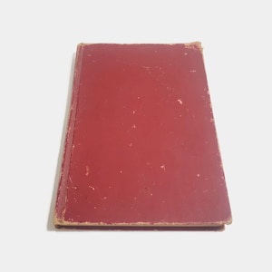 May include: A red hardback book with a worn, textured cover.