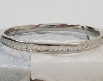 Op de afbeelding: Een zilveren armband met een decoratief gegraveerd ontwerp.