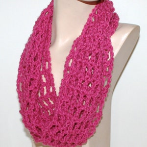 May include: A pink crocheted infinity scarf with a delicate openwork pattern.