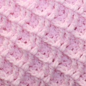 Op de afbeelding: Een close-up van een roze gehaakt stof met een textuurpatroon.