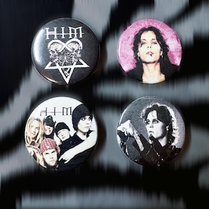 May include: Four round buttons featuring the band HIM. One button has the band's logo with a skull and pentagram design. Another has a portrait of a person with a cigarette. The other two buttons have band member portraits.