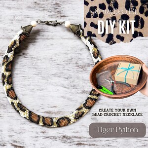 May include: DIY kit to create a Tiger Python bead crochet necklace. The kit includes beads, thread, and tools. The finished necklace is brown, black, and white with a leopard print pattern.