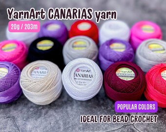 May include: A collection of 20 gram balls of YarnArt Canarias cotton mercerized yarn in various colors, including white, red, pink, purple, and black. The yarn is ideal for bead crochet.