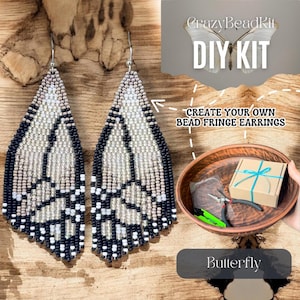 May include: A DIY kit for creating bead fringe earrings shaped like butterfly wings. The kit includes a small cardboard box with a blue ribbon, pliers, and two finished earrings featuring a black, white, and grey beaded wing pattern.