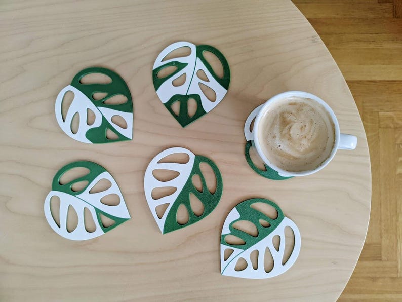 Multiple monstera adansonii leaf coasters arranged flat showing all coaster pieces