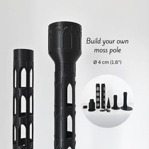 Pode incluir: Componentes pretos de plástico para postes de musgo. A imagem mostra dois postes montados e várias peças, incluindo uma base, conectores e uma peça em forma de cone. O texto diz "Build your own moss pole" e "Ø 4 cm (1,6")".