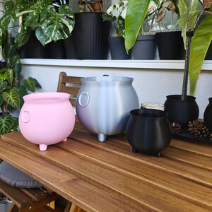 Set of cauldron planters on table, witch pot decor for home styling