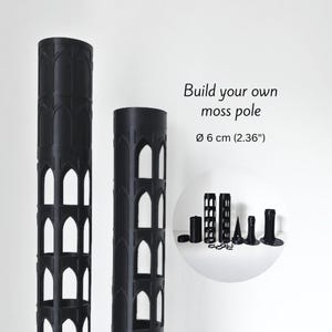 Peut inclure: Composants noirs pour tuteur à mousse avec découpes en forme d'arches. Le texte indique "Build your own moss pole" et "ø 6 cm (2.36")". Comprend diverses pièces pour l'assemblage, idéales pour soutenir les plantes grimpantes.