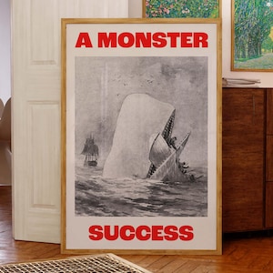 May include: A framed poster with a black and white illustration of a whale attacking a ship. The poster has the text "A MONSTER" at the top and "SUCCESS" at the bottom, both in red.