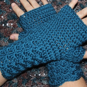 May include: A pair of teal blue crocheted fingerless gloves. The gloves are made with a simple stitch pattern and have a loose fit.