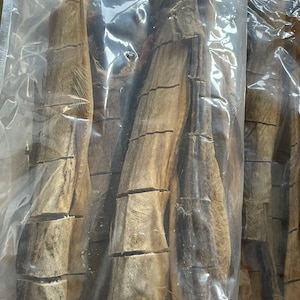 May include: A close-up of a plastic bag filled with dried fish. The fish is brown and has a rough texture. The bag is clear and shows the fish inside.