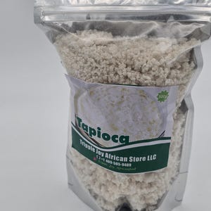 May include: A clear plastic bag filled with white tapioca pearls. The bag has a green label that says "Tapioca" and "Tripple Joy African Store LLC" with a phone number and the text "Tripple Joy Africanfood". The label also has a green sticker that says "500g".