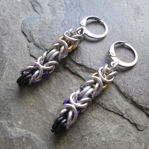 May include: A pair of silver, black, purple, and gold chain earrings with a hook closure.