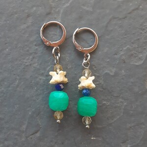 May include: A pair of earrings with silver hoops and a mix of turquoise, white, and blue beads.