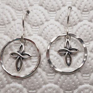May include: Silver dangle earrings with a Celtic knot cross charm inside a hammered circle.