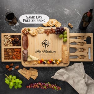 May include: A wooden serving board with a built-in drawer for cheese knives. The board is engraved with a compass and the text "The Madison 41°25' 37.8" N, 79°59' 12.4" W".