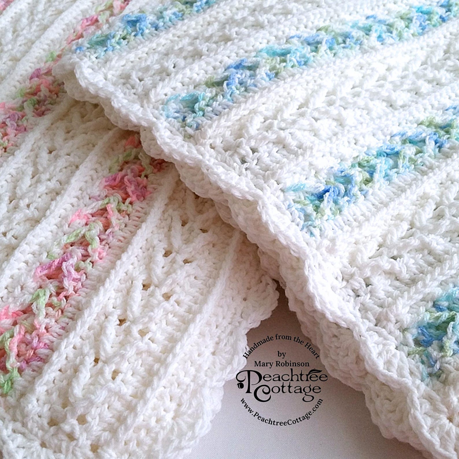 White baby blanket with pastel accent stripes and textured stitches, folded neatly