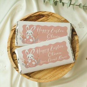 May include: Two white chocolate bar wrappers with pink bunny illustrations and the text "Happy Easter Olivia" and "Happy Easter Olivia Love Aunt Renee".