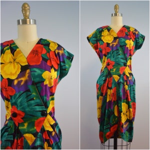 May include: A vibrant, tropical print dress with a wrap-style bodice and a short, fitted skirt. The dress features a mix of red, yellow, green, and purple flowers on a black background.